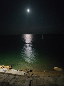 luna llena sobre el océano por la noche en Calypso Beach Hotel, en Loutra Edipsou
