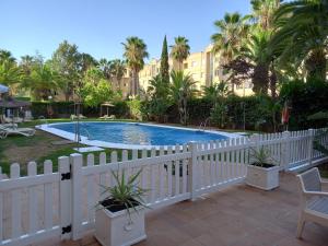a white fence around a swimming pool with palm trees at Hotel TRH La Motilla in Dos Hermanas