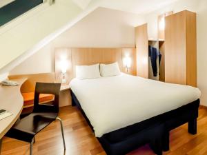 a bedroom with a large white bed and a desk at ibis Vannes in Vannes