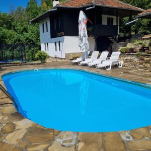 uma piscina azul com espreguiçadeiras e uma casa em АРНАТА КЪЩА em Yakovtsi