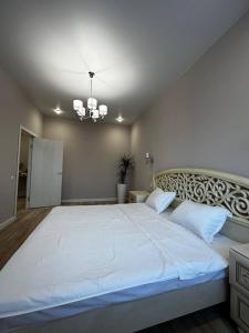 a large white bed in a bedroom with a chandelier at Новая квартира на Галактике in Uralsk +9 photos