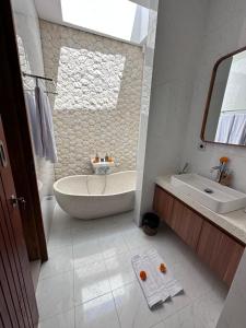 ein weißes Badezimmer mit einer Badewanne und einem Waschbecken in der Unterkunft Bali Bird Villa in Seminyak