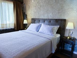 ein Schlafzimmer mit einem großen Bett mit weißer Bettwäsche und Kissen in der Unterkunft The Little Stone House by the Lake in Kastoria