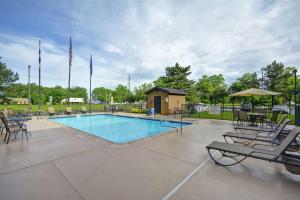 ein Pool mit Stühlen und ein Haus mit Flaggen in der Unterkunft Hampton Inn Detroit Madison Heights South Troy in Madison Heights