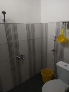 a bathroom with a shower with a toilet and a yellow bucket at Endah Homestay Syariah in Purwokerto