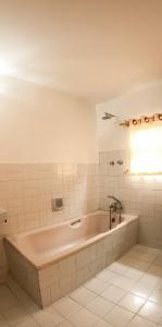 y baño de azulejos blancos con bañera. en Happy Days Inn, en Pokhara