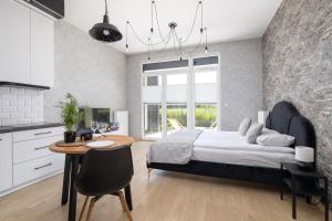 a bedroom with a bed and a table and a kitchen at Kraków Studio with Parking & Terrace near Zalew Bagry by Renters Prestige in Kraków