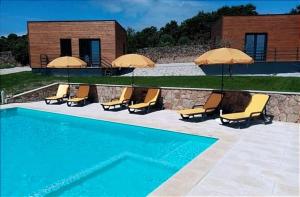 a pool with chairs and umbrellas next to a building at Trancoso Ecohouse in Trancoso