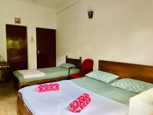 a room with two beds and a red chair at Crystal Lake Resort in Kandy