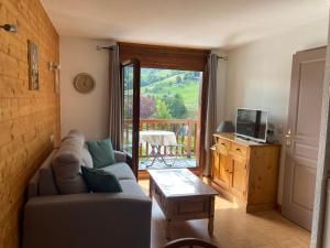 a living room with a couch and a table and a balcony at Les Chevreuils des Evettes in Flumet