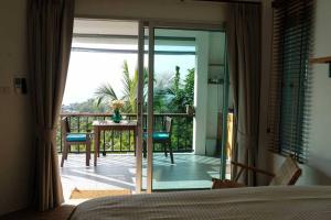 una camera da letto con porta a vetri che conduce a un balcone di The Love Nest - Stylish One Bed House a Ban Chalok Lam