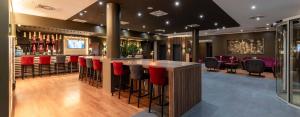 a bar in a restaurant with red bar stools at PLAZA Premium Karlsruhe in Karlsruhe