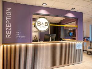 a bbb hotel lobby with a purple wall and a sign at B&B Hotel Schwerin-Süd in Schwerin
