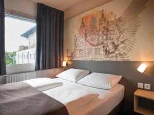 - une chambre avec 2 lits et un tableau mural dans l'établissement B&B Hotel Schwerin-Süd, à Schwerin