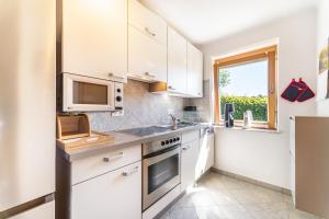 a kitchen with white cabinets and a microwave and a window at Ferienwohnung Auszeit 