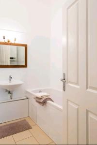 een witte badkamer met een wastafel en een deur bij Augarten Paradies in Wenen
