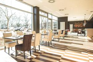 a restaurant with tables and chairs and windows at PLAZA Premium Karlsruhe in Karlsruhe