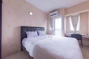 a bedroom with a large white bed and a window at RedLiving Apartemen Grand Sentraland - Dragon Apartel Tower Pink in Karawang +18 photos