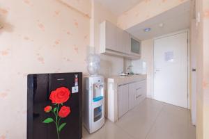 - une cuisine avec un réfrigérateur noir orné d'une rose dans l'établissement RedLiving Apartemen Grand Sentraland - Dragon Apartel Tower Pink, à Karawang