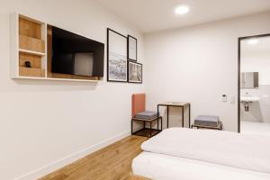 a white bedroom with a bed and a tv at SMARTments business Mannheim Hauptbahnhof in Mannheim