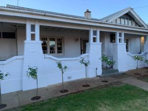 ein weißes Haus mit Bäumen davor in der Unterkunft Lee's on loftus in Temora