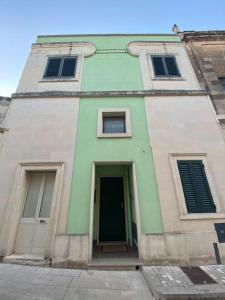 ein Gebäude mit grüner Tür und drei Fenstern in der Unterkunft Casa Vacanze Zia Meme in San Donato di Lecce