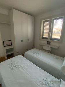 ein weißes Schlafzimmer mit 2 Betten und 2 Fenstern in der Unterkunft Casa Vacanze Zia Meme in San Donato di Lecce