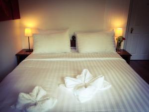 a white bed with two folded towels on it at Rosemead Guest House in Claygate