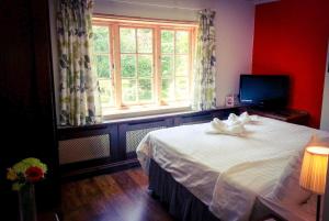 a bedroom with a large white bed with a window at Rosemead Guest House in Claygate