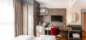 a hotel room with a desk and a red chair at PLAZA Premium Karlsruhe in Karlsruhe