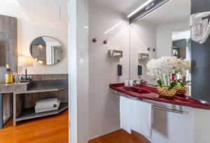 La salle de bains est pourvue d'un lavabo rouge et d'un miroir. dans l'établissement PLAZA Premium Karlsruhe, à Karlsruhe