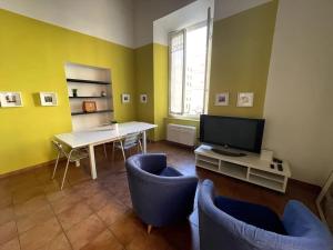 a living room with a table and chairs and a television at Loft storico in pieno centro! in Livorno