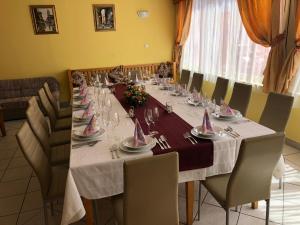 a long table with chairs and plates and wine glasses at City Hotel Siófok in Siófok