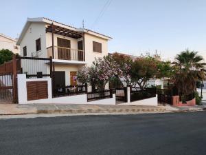 a white house with a fence and a street at Serena Vacation Home in Pomos