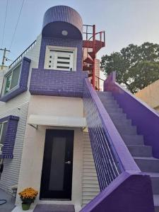 una casa con una barandilla de escalera púrpura y una escalera en Dongpirang Purple House 2, en Tongyeong