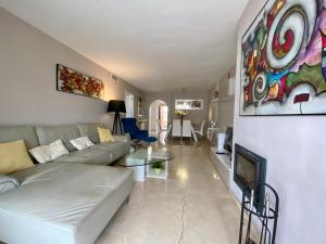 een woonkamer met een bank en een schilderij aan de muur bij Apartamento con vistas y terraza en Guadalmina Marbella in Marbella