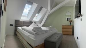 um quarto com uma cama com lençóis brancos e um banco em New Nomads Ferienwohnung am See em Zossen