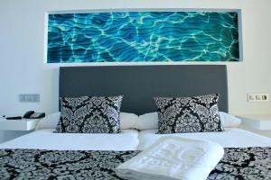 a bed with two pillows and a painting on the wall at BG Nautico Ebeso in Ibiza Town