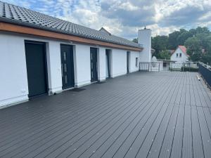 a large wooden deck with a white building at New Nomads Ferienwohnung am See in Zossen