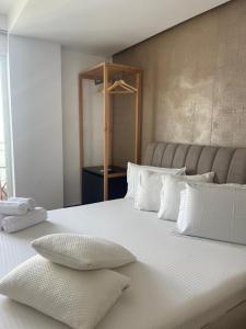 Una gran cama blanca con almohadas blancas. en Hotel Adria, en Shëngjin