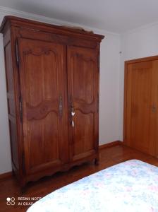 a wooden cabinet in a bedroom next to a bed at chez Sylvie et Alain 