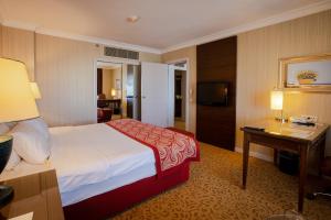 アンカラにあるBuyukhanli Park Hotelのベッド、デスク、テレビが備わるホテルルームです。