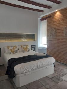 een slaapkamer met een groot bed met een bakstenen muur bij FLORIT FLATS - CENTER MODERN 1BR 2Bth TERRACE WI-FI AC in Valencia