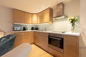 a kitchen with wooden cabinets and a vase of flowers at Kittiwake Cottage in Braunton