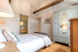 a bedroom with a white bed and a dresser at Kittiwake Cottage in Braunton