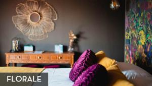 Un dormitorio con una cama con almohadas moradas y una mesa. en LES 7 MEUSES - Restaurant & Hébergements HÔTELIERS - INSOLITES - WELLNESS - GÎTES en Profondeville