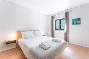 a white bedroom with a bed and a window at Fernandes Apartments in Ponte de Lima
