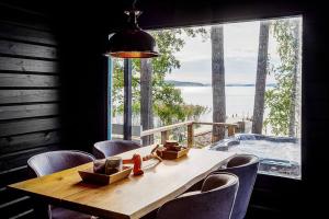 jadalnia ze stołem i krzesłami oraz dużym oknem w obiekcie Saunamäki L - Exquisite Luxurious Seafront Villa w mieście Salo