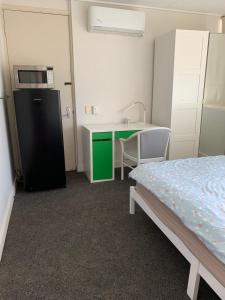 a room with a bed and a kitchen with a refrigerator at Adalong Student Guest House in Brisbane