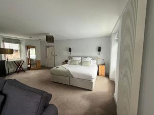 1 dormitorio con cama blanca y sofá en The Salutation Inn en Topsham